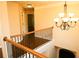 Bright hallway featuring a wooden handrail, decorative chandelier, and neutral-toned walls at 7940 White Oak Loop, Lithonia, GA 30038