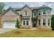 Charming two-story brick home featuring a well-manicured lawn, inviting entrance, and attached two-car garage at 316 Rodeo Dr, Auburn, GA 30011
