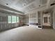 Living room featuring a tray ceiling, custom shelving, cabinetry, large windows, and unfinished walls at 839 Braselton Hwy, Lawrenceville, GA 30043