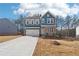 Two-story home featuring a stone facade, attached two-car garage, and a long concrete driveway at 7260 Eton Ln, Locust Grove, GA 30248