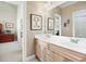 Double vanity bathroom with light wood cabinets and a view of an adjacent office at 2041 Democracy Dr, Buford, GA 30519