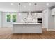 Modern kitchen with white cabinets, stainless steel appliances, large island, and hardwood floors at 4002 Adler Cir, Buford, GA 30519