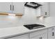 Close up of gas cooktop and white cabinets with quartz countertops and subway tile backsplash at 4002 Adler Cir, Buford, GA 30519