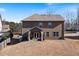 View of the house from the back showing the patio area, and large mostly brown lawn at 5915 Partners Pass, Cumming, GA 30028