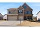 Beautiful two-story brick home with a three car garage, manicured lawn and inviting front porch at 5915 Partners Pass, Cumming, GA 30028