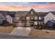 Elegant two-story home featuring a brick facade, a three-car garage, and a professionally landscaped front yard at dusk at 5915 Partners Pass, Cumming, GA 30028