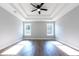 A bedroom featuring tray ceiling, modern ceiling fan, wood-look floors, and large windows at 4187 Mistymorn Way, Powder Springs, GA 30127