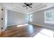 A bedroom featuring tray ceiling, modern ceiling fan, wood-look floors, and large windows at 4187 Mistymorn Way, Powder Springs, GA 30127