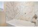 Clean bathroom with marble-tiled walls and a white bathtub at 1903 Meadow Ln, Decatur, GA 30032