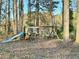 Backyard view featuring a swing set and slide between the mature trees on a sunny day at 3945 Peninsula Ct, Lawrenceville, GA 30044