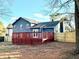 Home's backyard showcasing mature trees, a red deck, and a well maintained lawn in the winter at 3945 Peninsula Ct, Lawrenceville, GA 30044