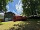 Home's backyard featuring a well maintained lawn, large deck, with mature trees on a sunny day at 3945 Peninsula Ct, Lawrenceville, GA 30044