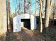 Outdoor shed with a door in the backyard with a lot of trees and leaves around the house at 3945 Peninsula Ct, Lawrenceville, GA 30044
