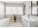Bright bathroom features dual sinks, white cabinets, modern fixtures, and a garden tub under a large window at 6750 Avis Walk, Alpharetta, GA 30005