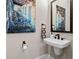 Powder room features a wall-mounted sink, dark fixtures, modern art, and a dark framed mirror at 6750 Avis Walk, Alpharetta, GA 30005