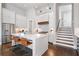 Well-lit kitchen with white cabinets, stainless steel appliances, an island with seating, and staircase access at 6750 Avis Walk, Alpharetta, GA 30005