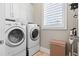 Modern laundry room featuring white cabinets, front-load washer and dryer, and a window with plantation shutters at 6750 Avis Walk, Alpharetta, GA 30005