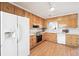 Kitchen with light wood cabinets, white appliances, and wood flooring at 1431 Willow Bend Dr, Snellville, GA 30078