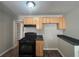 Kitchen showcasing wooden cabinets, dark countertops, black appliances and view into pantry at 854 Fayetteville Se Rd, Atlanta, GA 30316