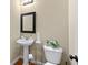 Small half bath features a pedestal sink, toilet, and decorative wall mirror and sconces at 3413 Talking Creek Ct, Conyers, GA 30094