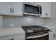 Modern kitchen features stainless steel microwave and range, gray backsplash, and quartz countertops at 4529 Twinberry Dr, Powder Springs, GA 30127