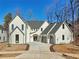 Charming two-story white home with a well-manicured lawn, gray roof and arched doorway and driveway at 120 Thome Dr, Alpharetta, GA 30022