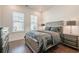 Cozy bedroom with a gray upholstered bed, wood floors, and natural light from two windows at 104 Ivey Way, Woodstock, GA 30188