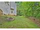A grassy backyard with a fence, fire pit and wooded boundary at 625 Piping Rock Pt, Lawrenceville, GA 30043