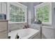 Bathroom with natural light, featuring a soaking tub beneath two windows offering green views at 625 Piping Rock Pt, Lawrenceville, GA 30043