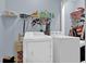 Bright laundry room with a full-size washer and dryer and storage shelving at 625 Piping Rock Pt, Lawrenceville, GA 30043