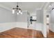 Dining room with hardwood floors leads to the kitchen with white cabinets and black backsplash at 2170 Charleston Pl, Lithia Springs, GA 30122