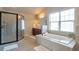 Bright bathroom features a soaking tub, tiled shower, and large window at 200 Claret Way, Mcdonough, GA 30252