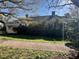 View of house surrounded by mature trees with lawn and concrete sidewalk at 5121 Newark Ave, Clarkdale, GA 30111