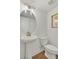 Elegant powder room with pedestal sink, toilet, and oval mirror at 1084 Battery Park Rd, Decatur, GA 30033