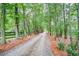 Long gravel driveway lined with mature trees and a wooden fence providing privacy at 1109 Wiley Bridge Rd, Woodstock, GA 30188