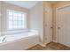 Bathroom offers a soaking tub beneath a window and a separate door leading to another room at 4671 W Lake Se Dr, Conyers, GA 30094
