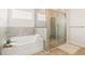 Well-lit bathroom features a tub with tile surround and glass enclosed shower at 7710 Tiberon Pkwy, Cumming, GA 30028