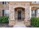 Inviting front porch with stone archway, black door, and decorative details at 7710 Tiberon Pkwy, Cumming, GA 30028