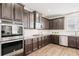 Kitchen with stainless appliances, a gas cooktop, granite counters, and rich dark wood cabinets at 7710 Tiberon Pkwy, Cumming, GA 30028