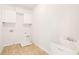Bright laundry room with tile floors, built in shelves and utility sink at 7710 Tiberon Pkwy, Cumming, GA 30028