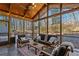 Relaxing sunroom featuring vaulted wood ceiling, tile floor and comfortable seating with view of wooded backyard at 96 Grand Ave, Suwanee, GA 30024
