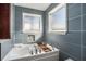 Modern bathtub featuring blue tiling, a mosaic shelf, and frosted windows at 3979 Doral Cir, Atlanta, GA 30360