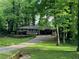 Traditional one-story brick home nestled among mature trees with a front deck and a driveway at 4876 Velva Nw Way, Lilburn, GA 30047