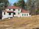 View of two-story home with red roof in construction phase and covered with protective wrap at 515 Penny Ln, Loganville, GA 30052