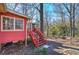 Red home exterior with a wooden deck, lush greenery, and mature trees at 731 Willow Ridge Dr, Marietta, GA 30068