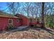Red home exterior with a wooden deck, lush greenery, and mature trees at 731 Willow Ridge Dr, Marietta, GA 30068