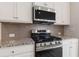 Modern kitchen with a stainless steel gas range, granite countertops and gray tiled backsplash at 4311 Portsbrook Ave, Snellville, GA 30039