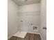 Small, simple laundry room with overhead wire rack, wood flooring, and utility sink at 4311 Portsbrook Ave, Snellville, GA 30039