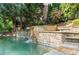Stone wall with cascading waterfall flowing into a backyard pool at 2960 Millwater Xing, Dacula, GA 30019