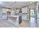 Spacious kitchen boasts white cabinets, stainless steel appliances, an island, and light wood flooring at 2106 Lacroix Way, Conyers, GA 30094